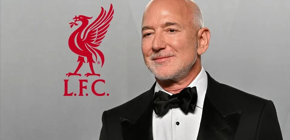 Hombre con traje en evento junto a logo de Liverpool