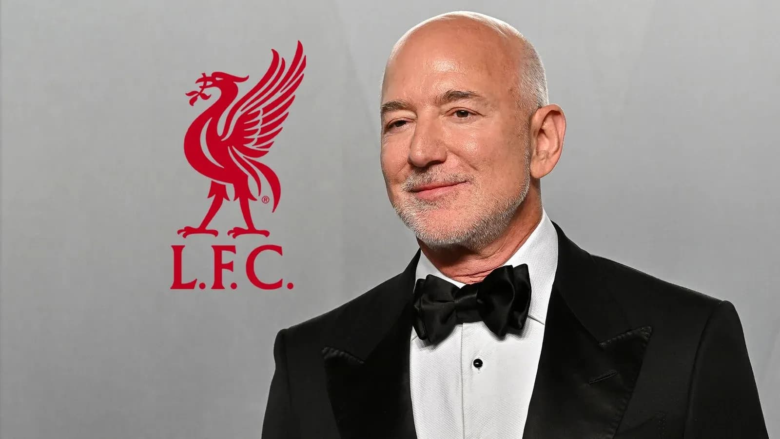 Hombre con traje en evento junto a logo de Liverpool