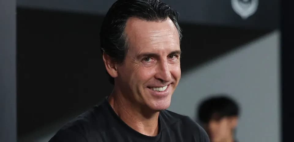 Entrenador sonriendo en el banquillo durante el partido