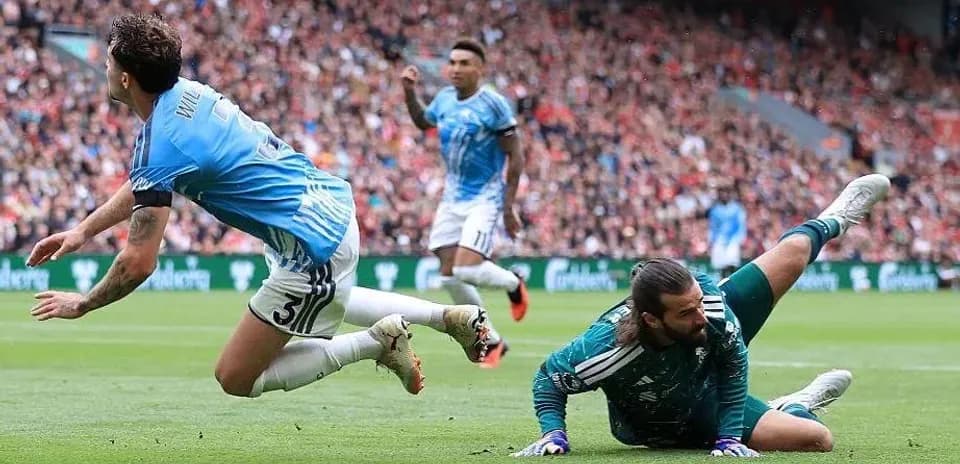 Jugador cae mientras el portero atrapa el balón