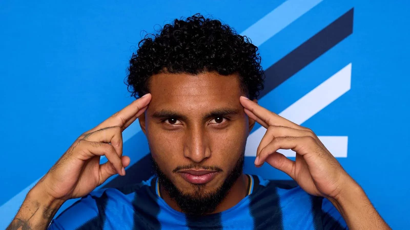 Jugador posando con fondo azul y gesto pensativo