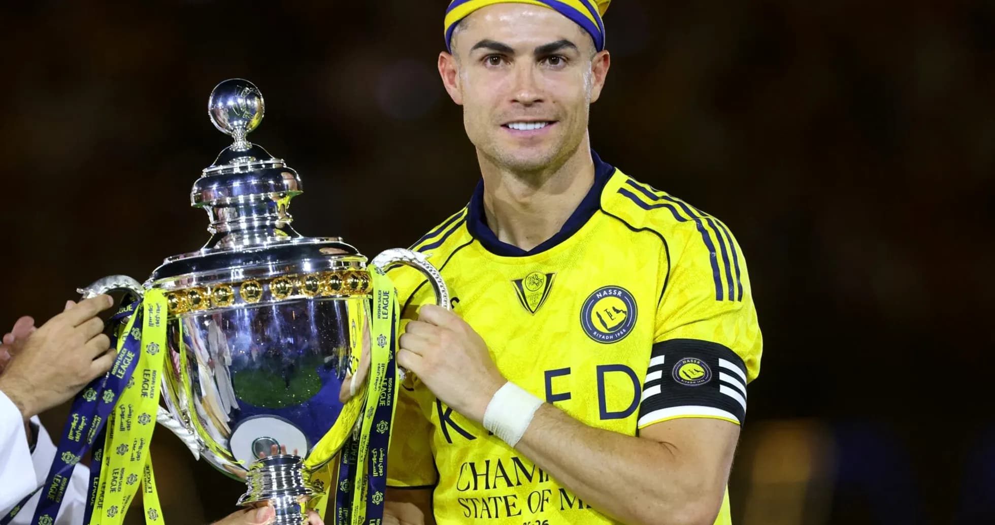 Jugador sosteniendo trofeo en uniforme amarillo Jugador sosteniendo trofeo en uniforme amarillo