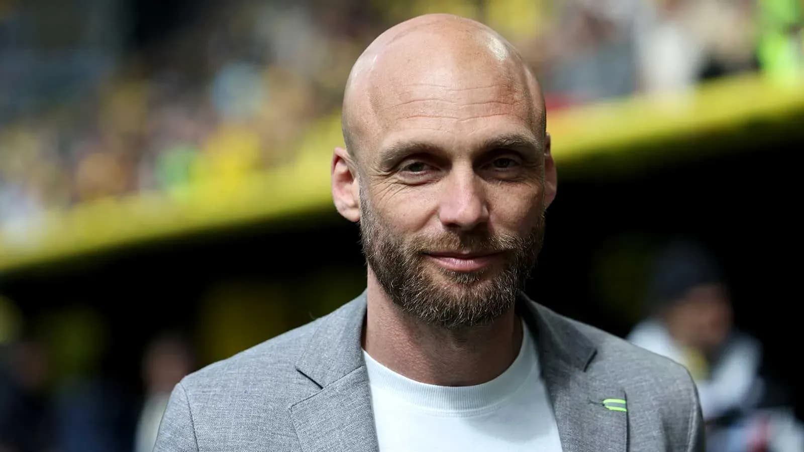 Hombre con traje gris sonriendo en el estadio Hombre con traje gris sonriendo en el estadio
