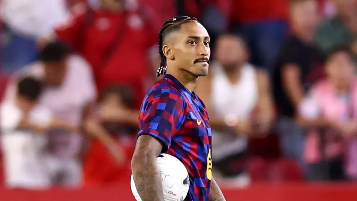 Jugador de fútbol sosteniendo un balón en el campo Jugador de fútbol sosteniendo un balón en el campo