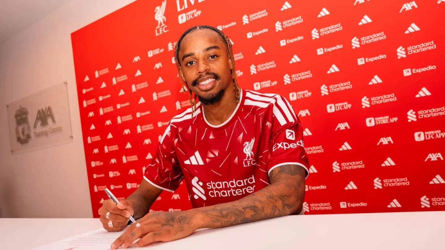 Jugador de Liverpool firmando contrato en mesa Jugador de Liverpool firmando contrato en mesa