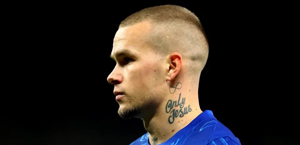 Jugador en perfil con tatuajes visibles y camiseta azul Jugador en perfil con tatuajes visibles y camiseta azul