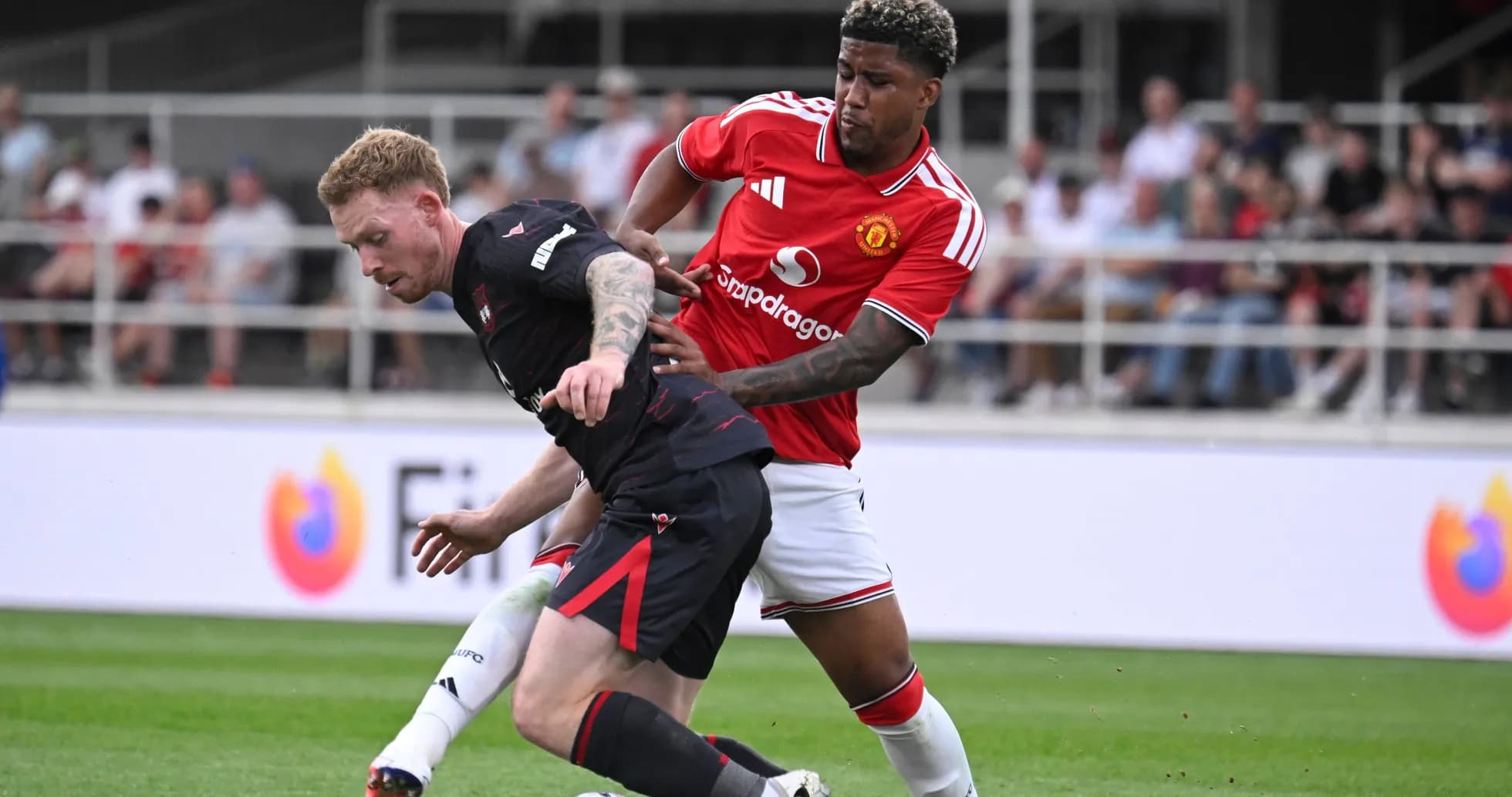 Jugador de Manchester United persiguiendo a oponente en el campo Jugador de Manchester United persiguiendo a oponente en el campo