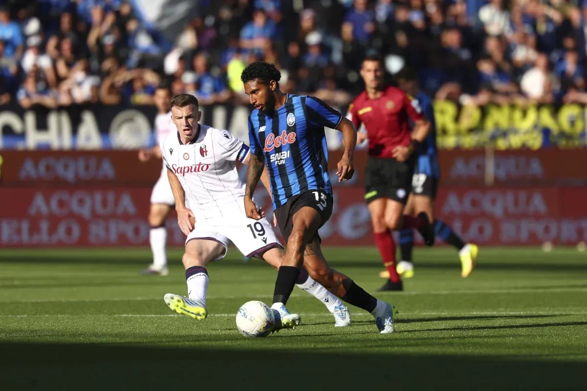Jugador de Atalanta driblando a rival de Bologna Jugador de Atalanta driblando a rival de Bologna