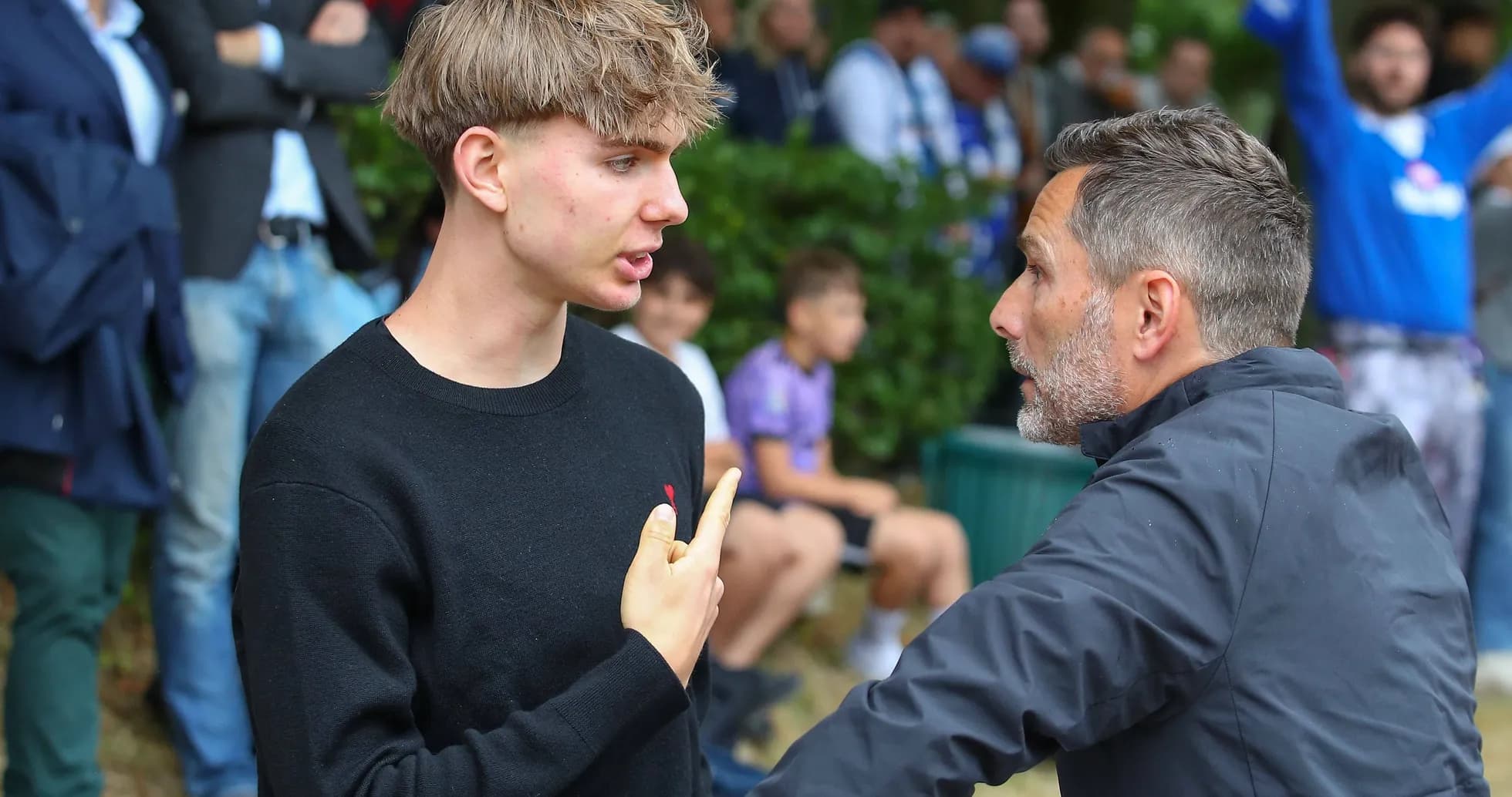 Dos hombres conversando intensamente en un evento deportivo Dos hombres conversando intensamente en un evento deportivo