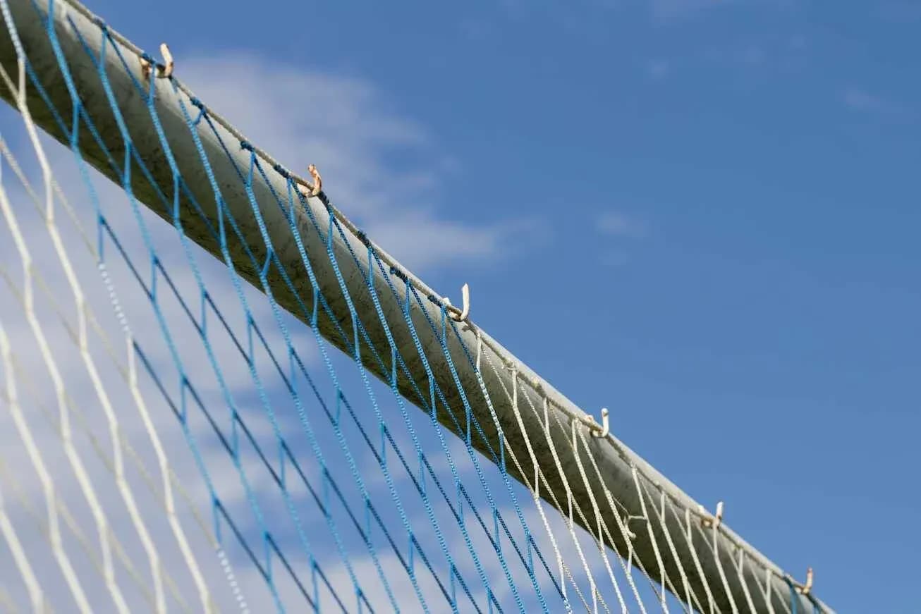 Red de un arco de fútbol contra un cielo azul Red de un arco de fútbol contra un cielo azul