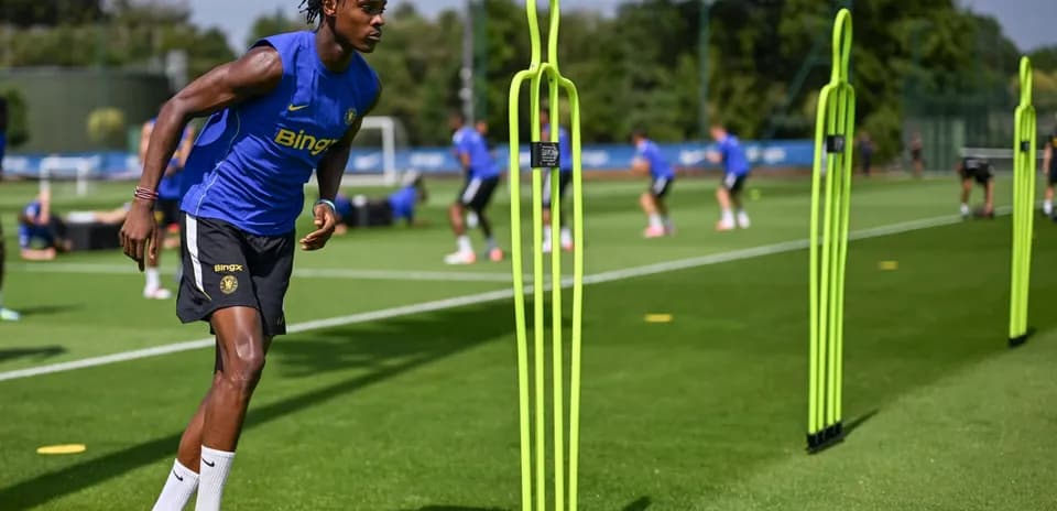 Jugador entrenando en campo con conos de entrenamiento Jugador entrenando en campo con conos de entrenamiento
