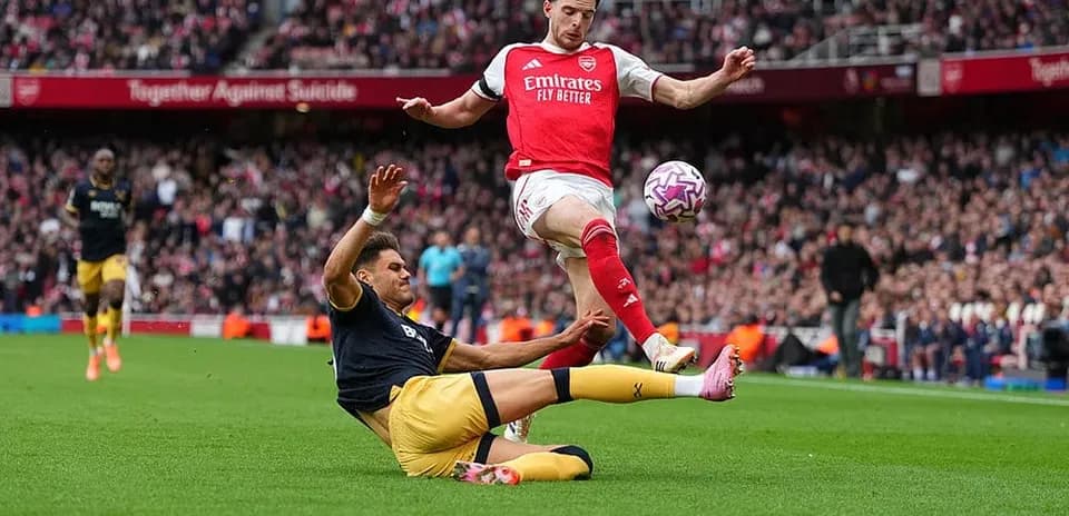 Jugador de Arsenal saltando sobre oponente de West Ham Jugador de Arsenal saltando sobre oponente de West Ham