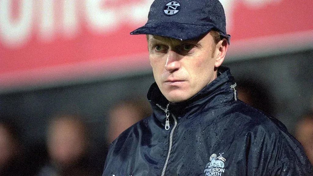 Entrenador de fútbol con chaqueta y gorra en campo Entrenador de fútbol con chaqueta y gorra en campo