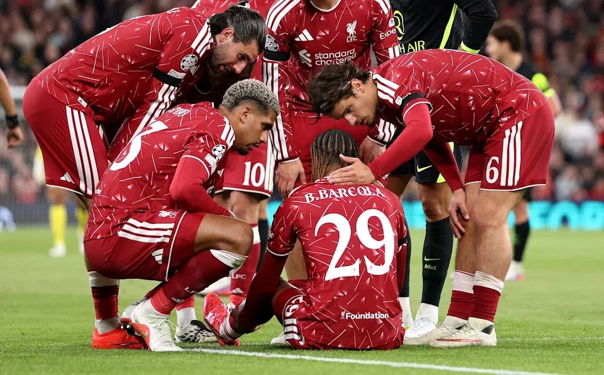 Jugadores de Liverpool apoyando a compañero en el suelo Jugadores de Liverpool apoyando a compañero en el suelo