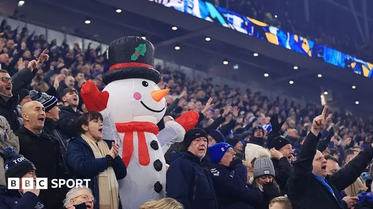 A crowd cheering with a large snowman mascot A crowd cheering with a large snowman mascot