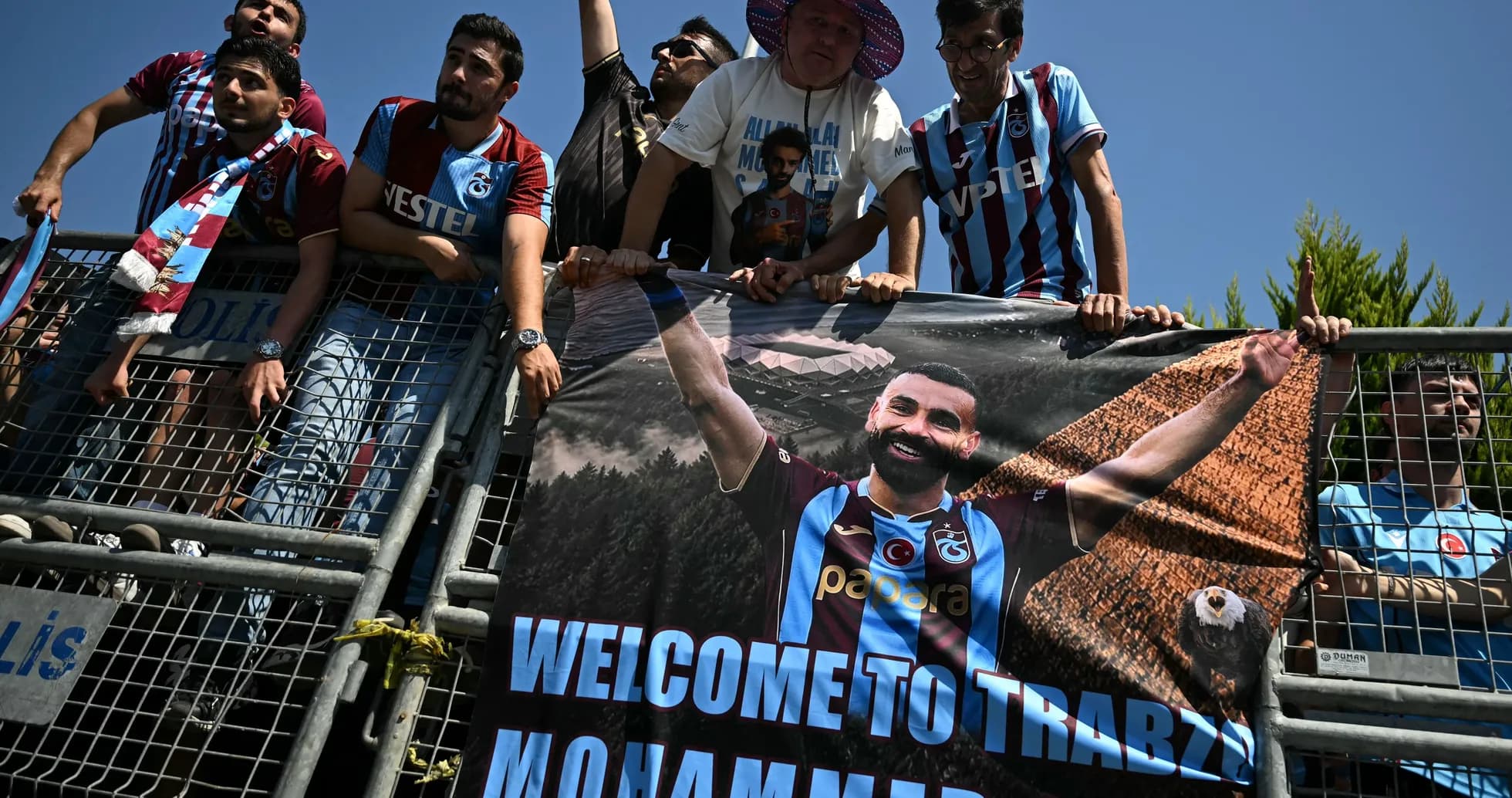 Aficionados sosteniendo un cartel de bienvenida en el estadio Aficionados sosteniendo un cartel de bienvenida en el estadio