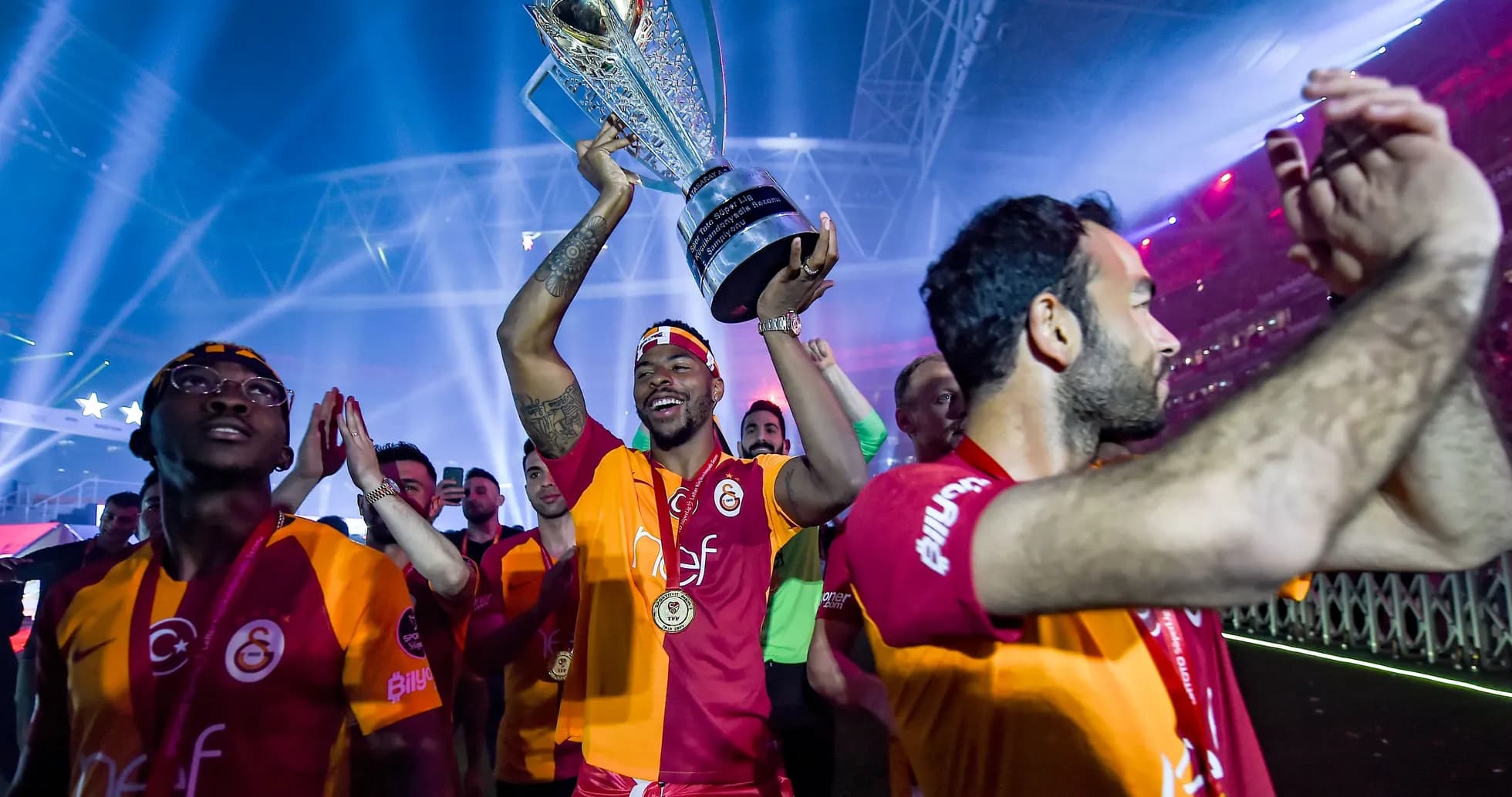 Jugador levantando trofeo con compañeros celebrando Jugador levantando trofeo con compañeros celebrando