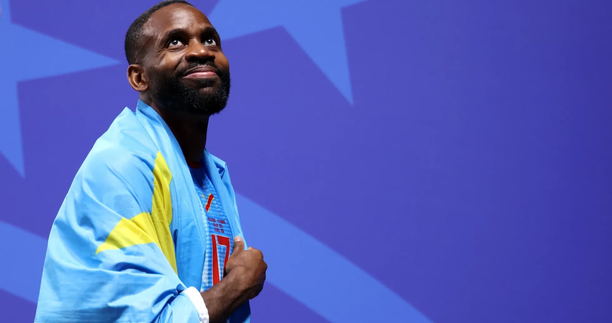 Atleta envuelto en bandera sonriendo en escenario Atleta envuelto en bandera sonriendo en escenario