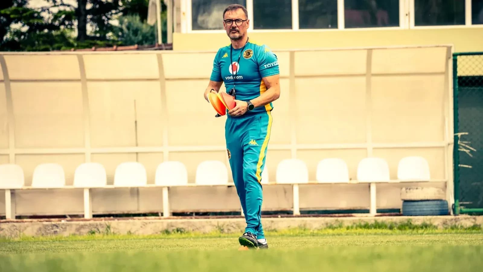 Entrenador sosteniendo conos en campo de entrenamiento Entrenador sosteniendo conos en campo de entrenamiento