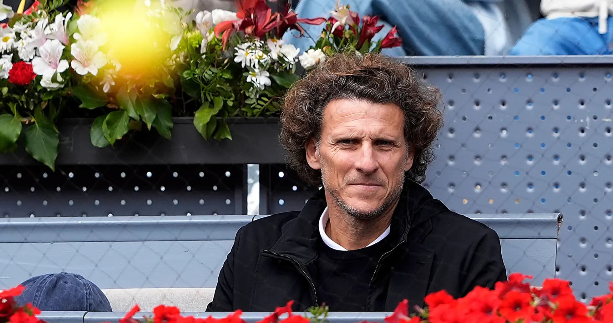 Hombre sentado entre flores en un evento deportivo Hombre sentado entre flores en un evento deportivo