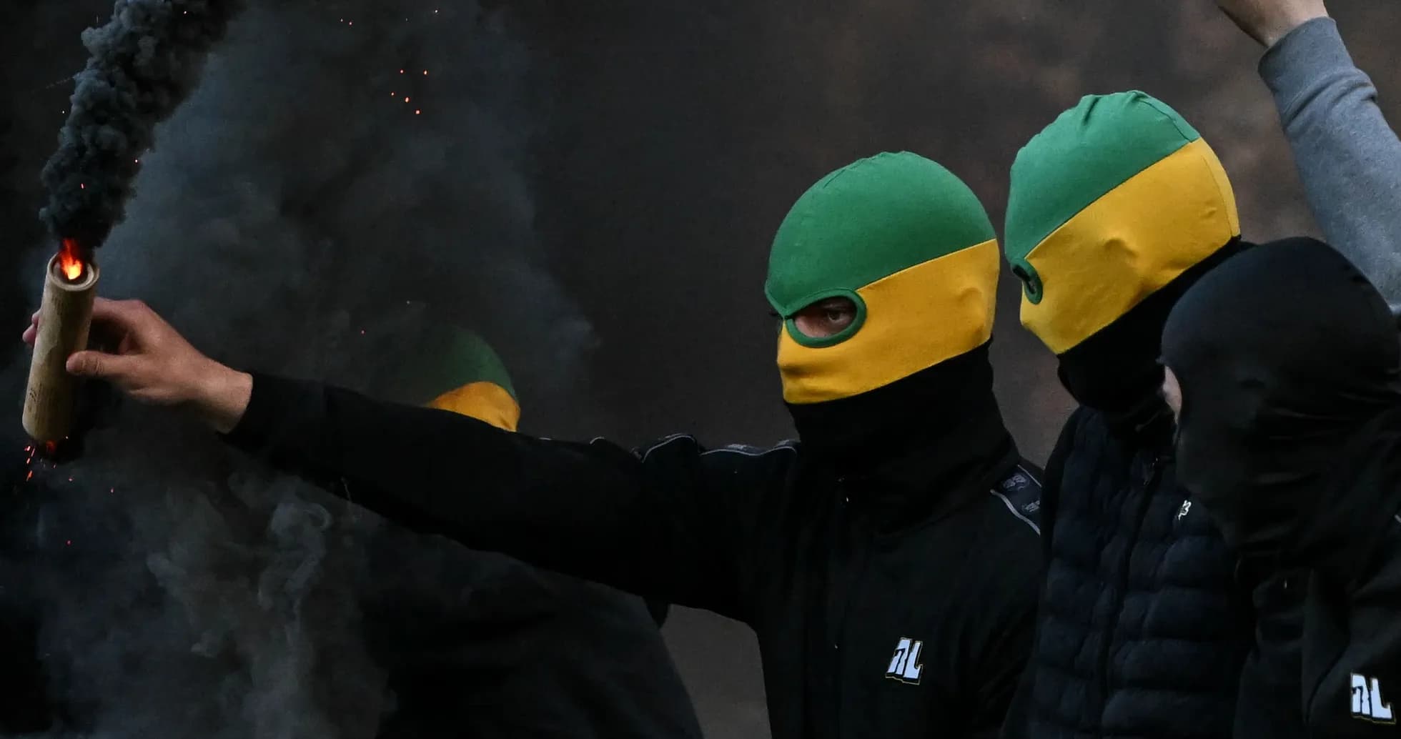 Personas con pasamontañas sosteniendo un artefacto incendiario Personas con pasamontañas sosteniendo un artefacto incendiario