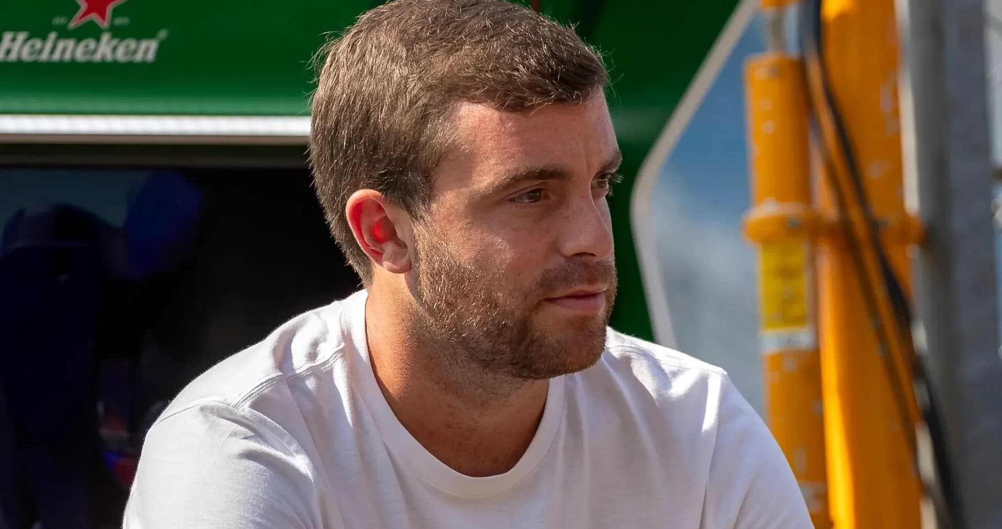 Hombre sentado con camiseta blanca en evento deportivo Hombre sentado con camiseta blanca en evento deportivo