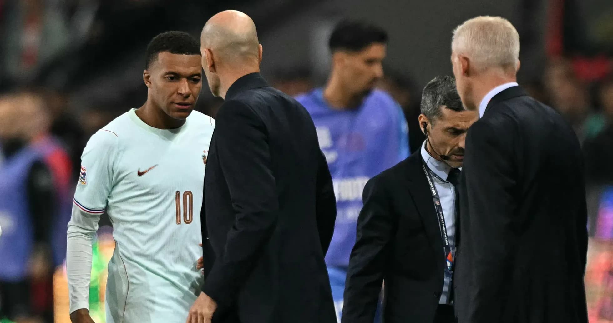 Kylian Mbappé conversando con entrenadores en el campo Kylian Mbappé conversando con entrenadores en el campo