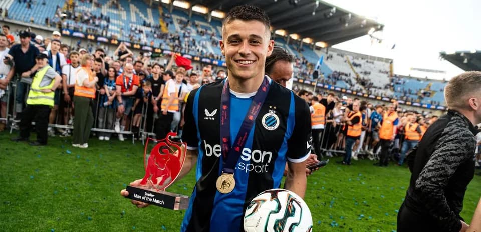 Jugador sosteniendo trofeo y balón en el campo Jugador sosteniendo trofeo y balón en el campo