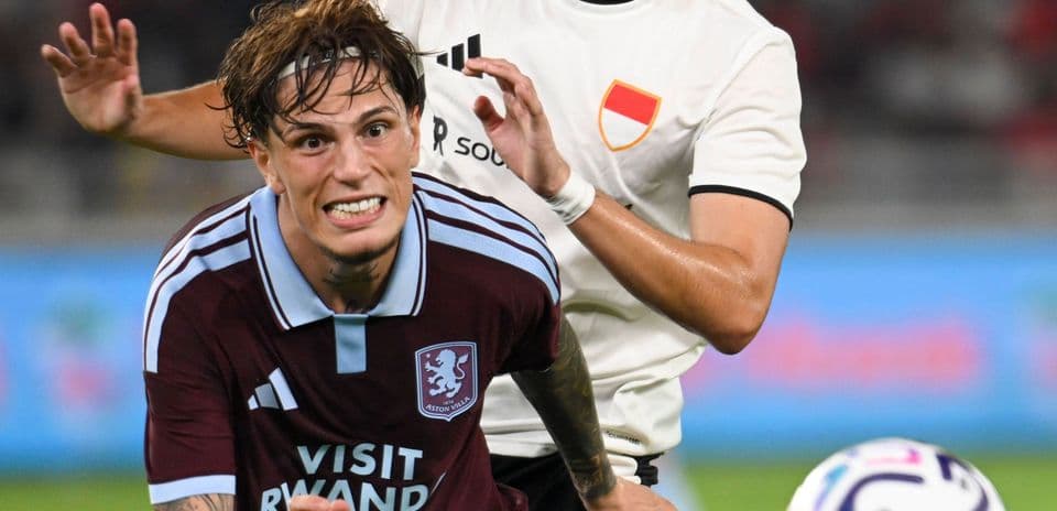 Jugador de Aston Villa siendo derribado por oponente Jugador de Aston Villa siendo derribado por oponente