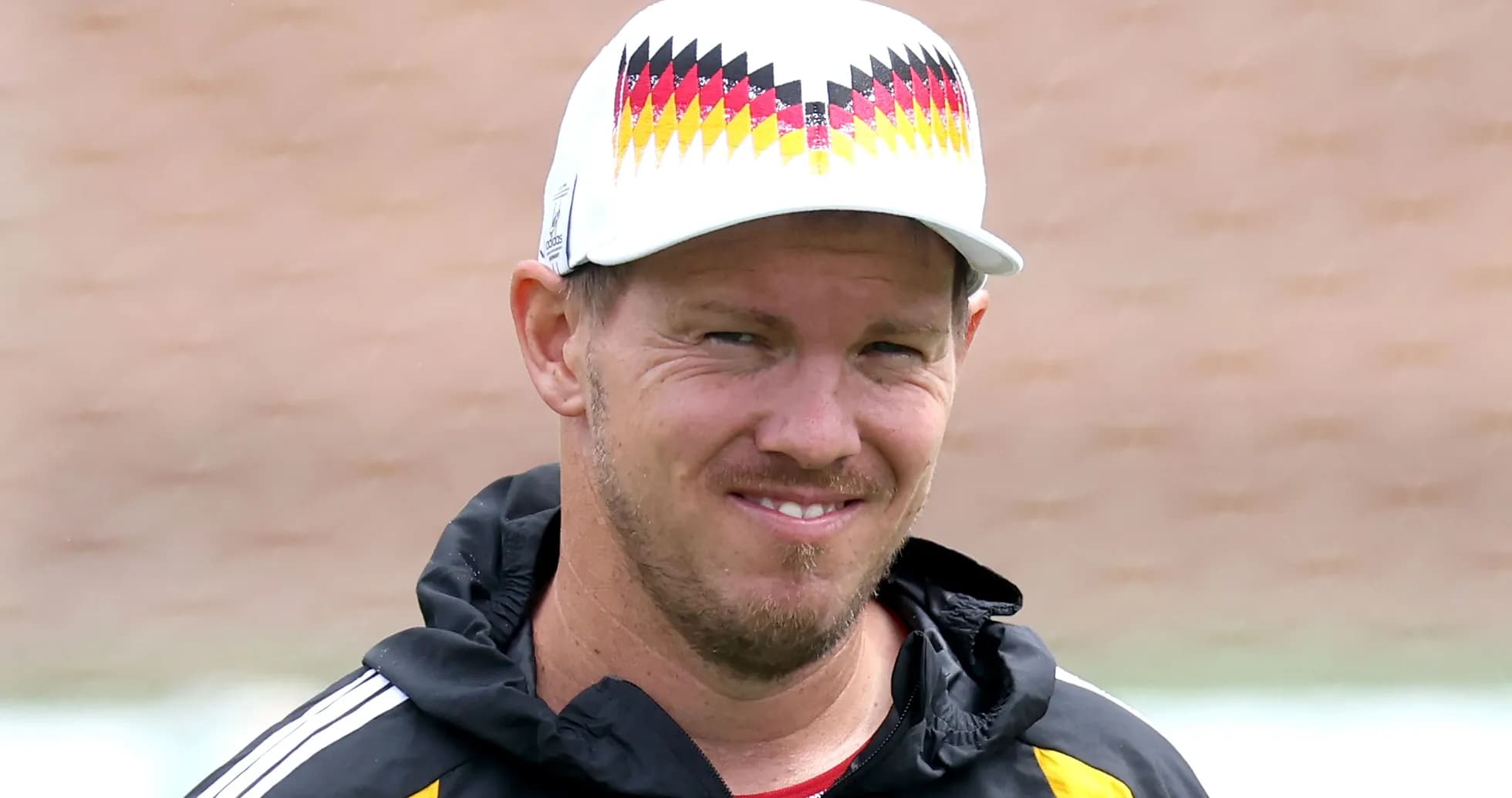 Entrenador sonriente con gorra en campo de entrenamiento Entrenador sonriente con gorra en campo de entrenamiento